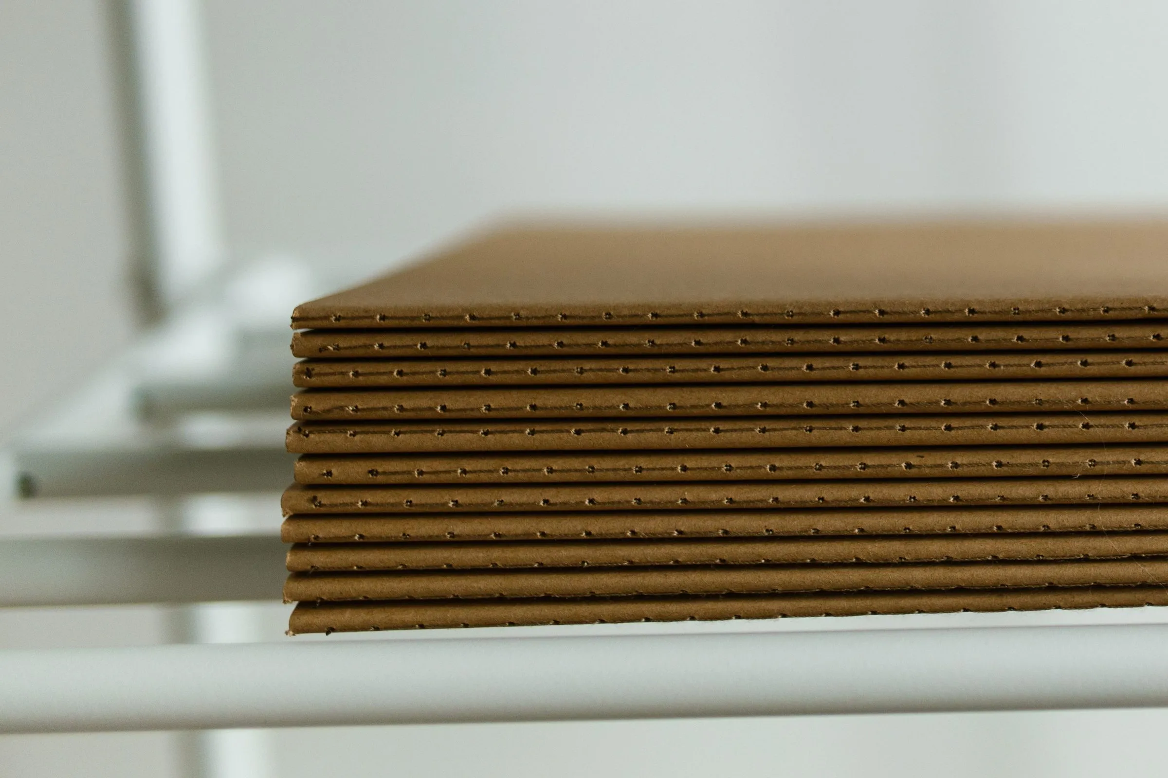A neat stack of single-wall corrugated board sheets resting on a white metal rack.