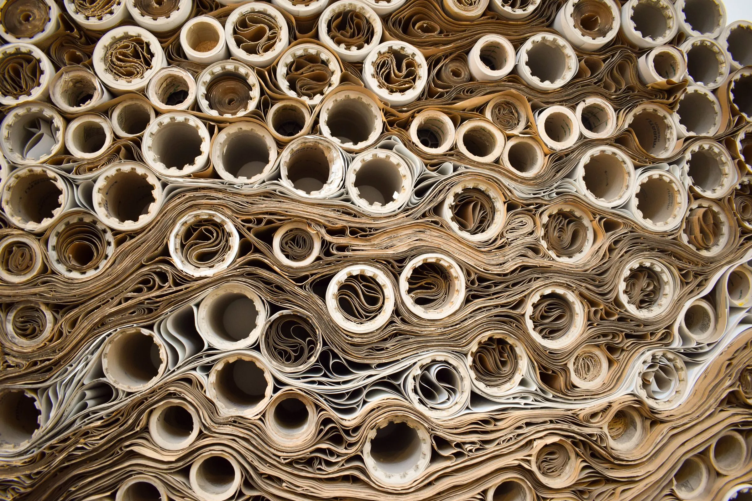 Rolled corrugated and kraft paper wound around paper cores, stacked end-on.